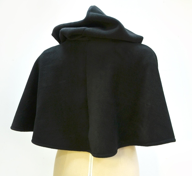 Black fleece cape shown from the back. It has a hood and it finishes just before the waist.