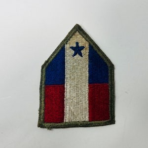 May include: A green, red, white, and blue embroidered patch with a single white star in the center. The patch is shaped like a triangle with rounded corners.