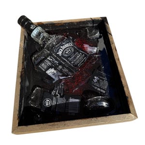 May include: A wooden tray with a black resin insert featuring a Jack Daniel's bottle and ice cubes. The resin is glittery and has a red tint.