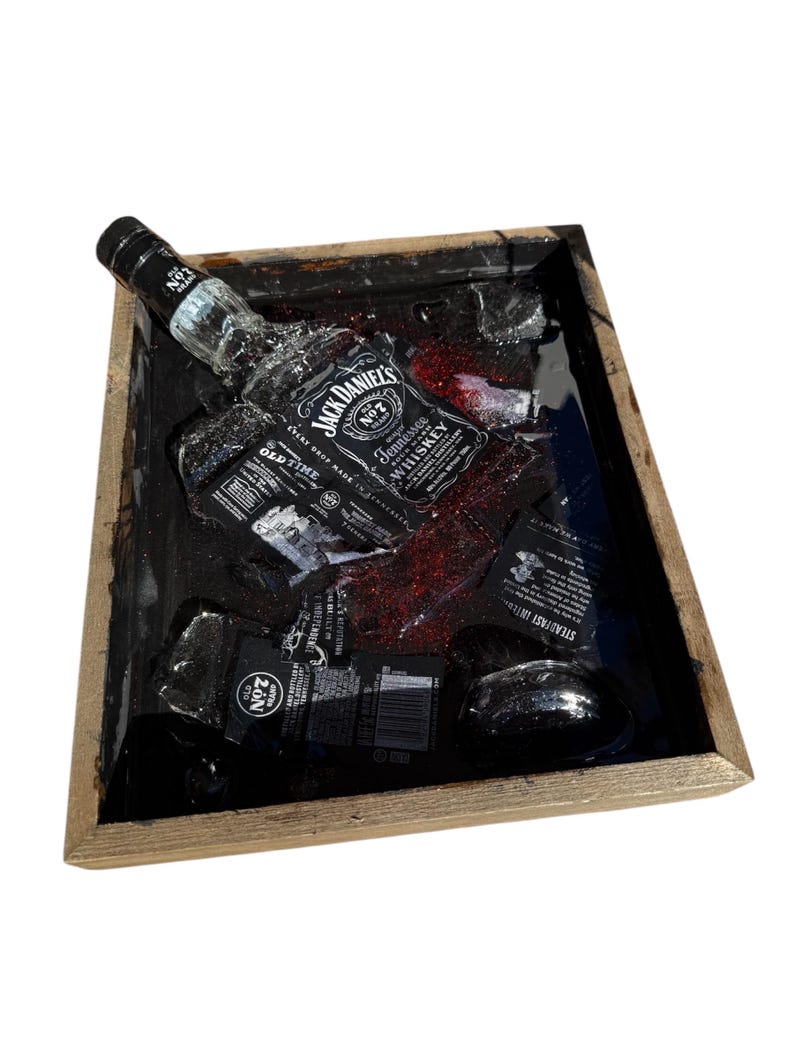 May include: A wooden tray with a black resin insert featuring a Jack Daniel's bottle and ice cubes. The resin is glittery and has a red tint.