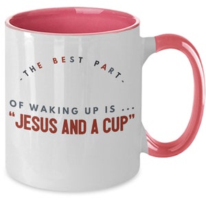 May include: White ceramic coffee mug with a pink rim and handle. The mug has a quote that reads "The best part of waking up is... "Jesus and a cup""