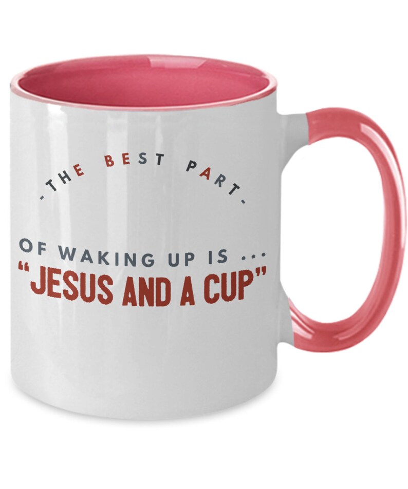 May include: White ceramic coffee mug with a pink rim and handle. The mug has a quote that reads "The best part of waking up is... "Jesus and a cup""