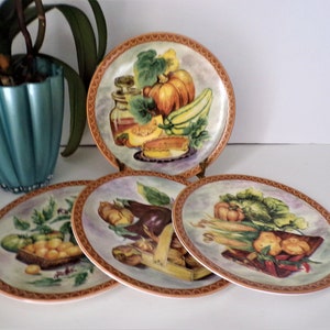 May include: Set of four ceramic salad plates featuring a colorful still life of various vegetables and fruits. Each plate has a different arrangement of produce, including pumpkins, squash, peppers, corn, and eggplant. The plates have a brown rim with a decorative pattern.