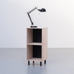 May include: A two-shelf wooden bookcase with black shelves and black metal legs. A black desk lamp with a black shade is on top of the bookcase.