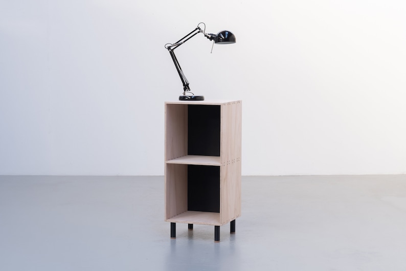 May include: A two-shelf wooden bookcase with black shelves and black metal legs. A black desk lamp with a black shade is on top of the bookcase.