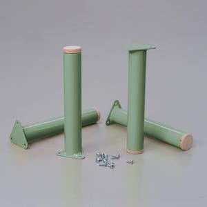May include: Four green metal table legs with wooden tops. The legs are triangular at the base and have a round top. There are also several screws scattered on the floor.
