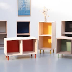 May include: Six wooden shelves with two shelves each. The shelves are painted in different colors, including red, yellow, green, and blue. The shelves are on wooden legs.