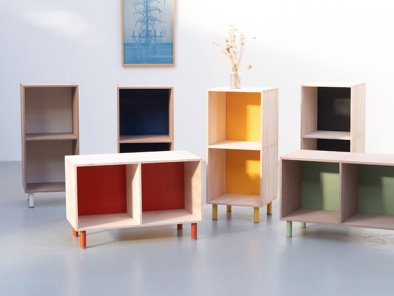 May include: Six wooden shelves with two shelves each. The shelves are painted in different colors, including red, yellow, green, and blue. The shelves are on wooden legs.