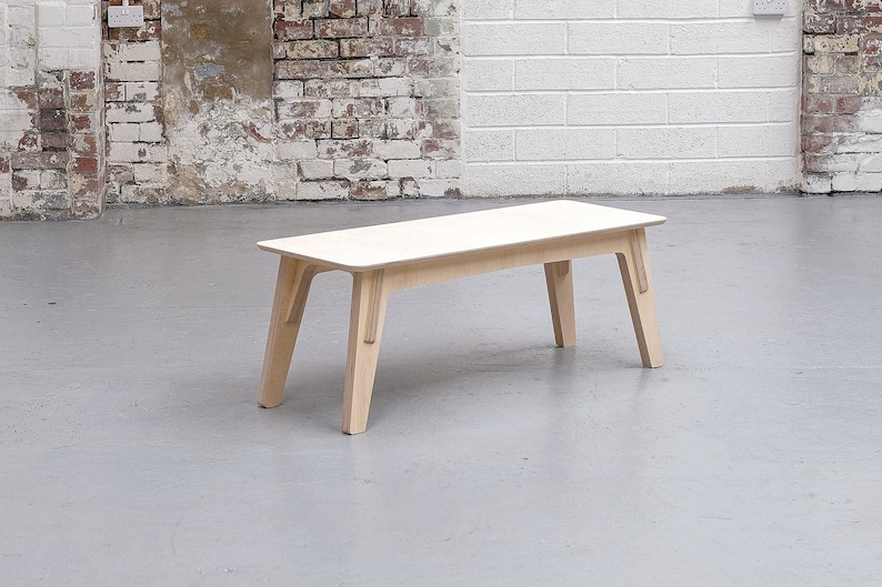 Puede incluir: Una mesa de centro de madera clara con una tapa rectangular y cuatro patas. La mesa tiene un dise&ntilde;o simple y moderno.