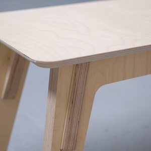 Puede incluir: Una mesa de madera clara con un dise&ntilde;o sencillo. La mesa tiene una tapa rectangular y cuatro patas. Las patas son anguladas y tienen una forma ligeramente curvada.