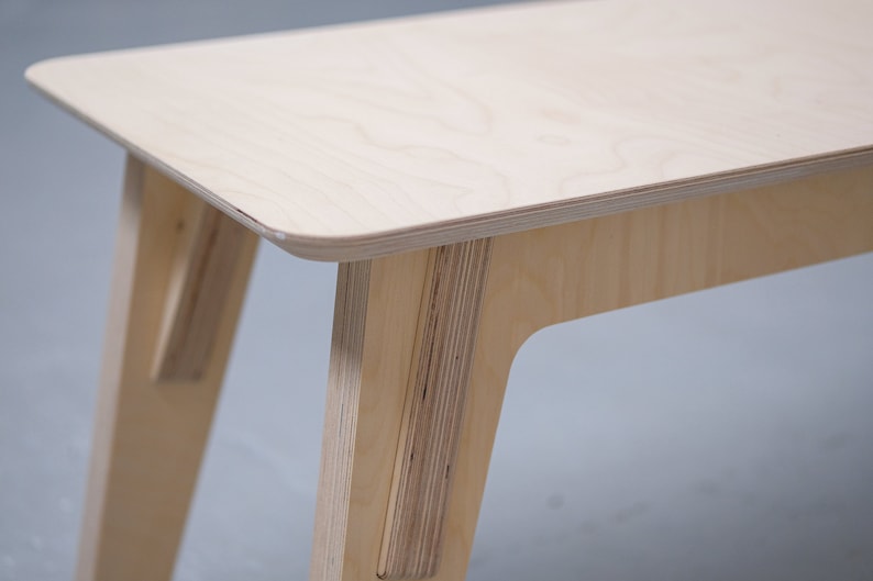 Puede incluir: Una mesa de madera clara con un dise&ntilde;o sencillo. La mesa tiene una tapa rectangular y cuatro patas. Las patas son anguladas y tienen una forma ligeramente curvada.