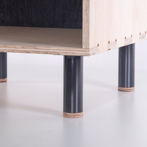 May include: A wooden shelf unit with four black legs. The shelf has a single open compartment.