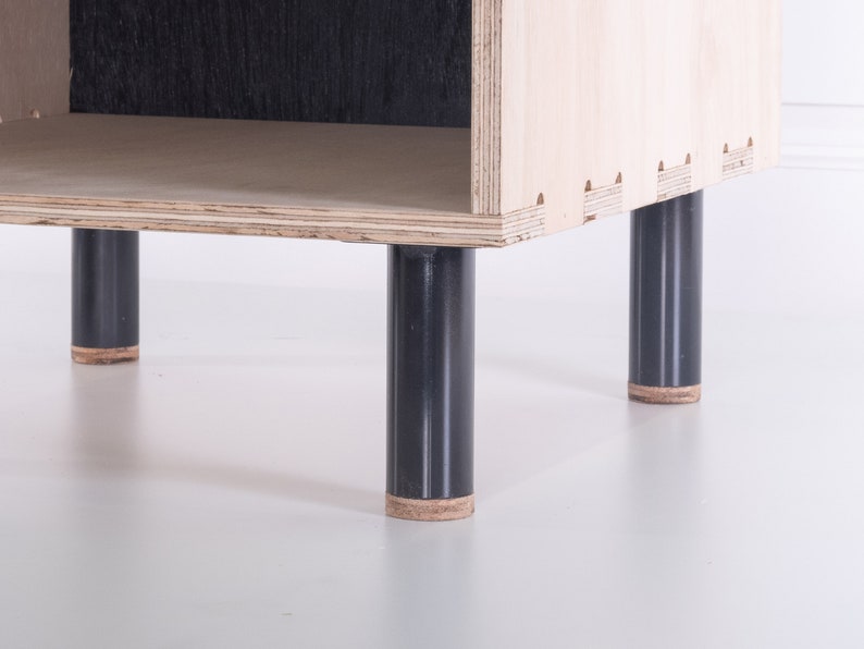 May include: A wooden shelf unit with four black legs. The shelf has a single open compartment.