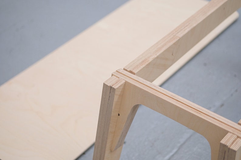 Puede incluir: Primer plano de un marco de mesa de madera que se est&aacute; ensamblando. El marco est&aacute; hecho de madera contrachapada y tiene un acabado de madera natural. El marco se est&aacute; ensamblando con una uni&oacute;n de inglete.