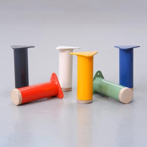May include: Five different colored metal table legs with a triangular base. The legs are painted black, white, yellow, green, and red.