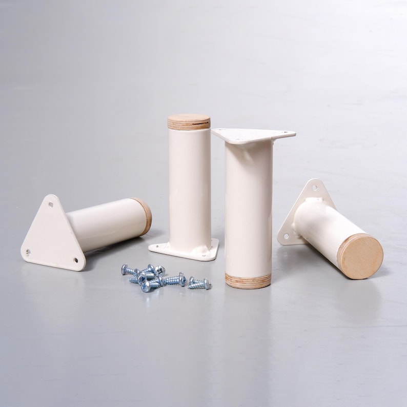 May include: Four white metal furniture legs with a wood top. The legs have a triangular base and are approximately 10 inches tall. The legs are accompanied by a set of screws.