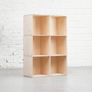 May include: A light wood bookshelf with six open shelves. The shelves are arranged in a 2x3 grid.