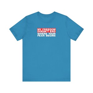 Op de afbeelding: Een lichtblauw t-shirt met een rode rechthoek waarop staat "My Freedom Doesn't End Where Your Fear Begins".