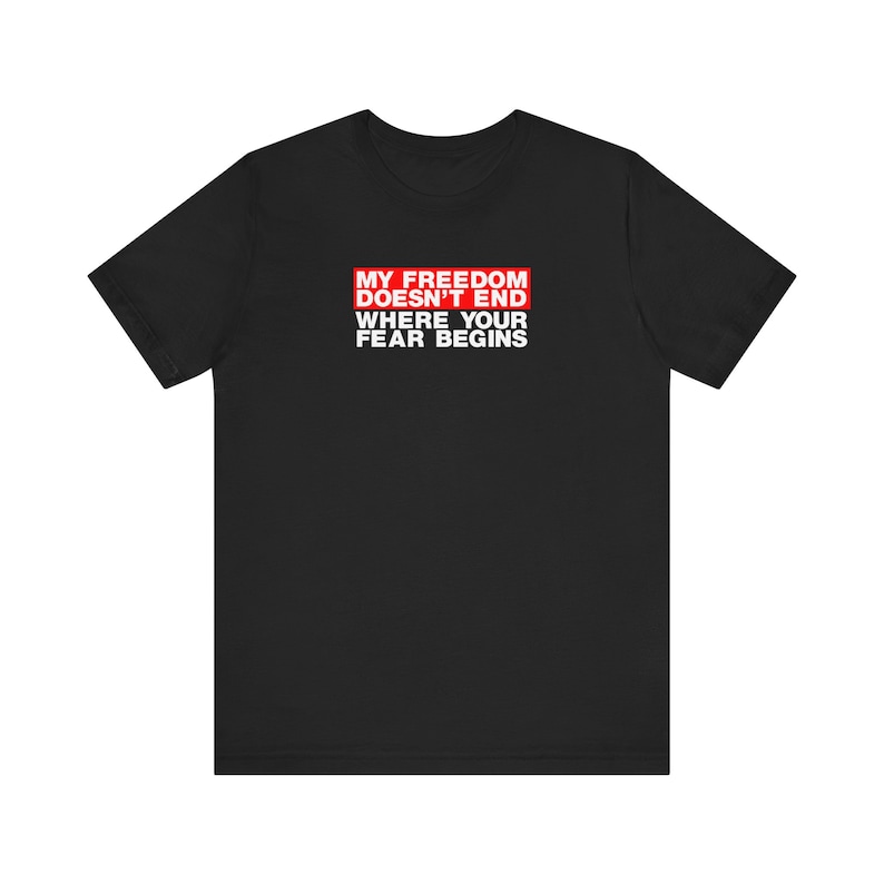 Op de afbeelding: Zwart T-shirt met een rode rechthoek en witte tekst die "Mijn vrijheid eindigt niet waar jouw angst begint." luidt.