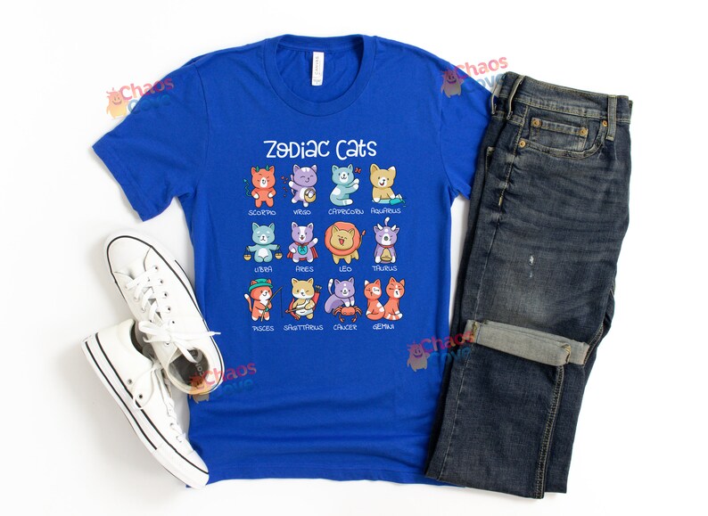 May include: A royal blue t-shirt with a graphic of zodiac cats. The cats are depicted in their respective zodiac signs, with each cat wearing a different color and design. The text "Zodiac Cats" is printed in white above the graphic.