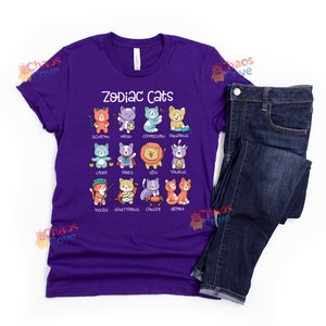 May include: Purple t-shirt with a graphic of cats representing each zodiac sign. The text "Zodiac Cats" is printed on the shirt.