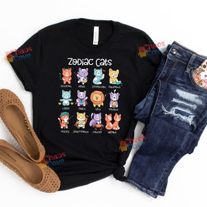May include: Black t-shirt with a graphic of zodiac signs represented by cats. The text "Zodiac Cats" is printed in white at the top of the graphic.