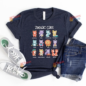 May include: A navy blue t-shirt with the text "Zodiac Cats" and a graphic of 12 cats representing the zodiac signs. Each cat is wearing a different costume and has a different color scheme.
