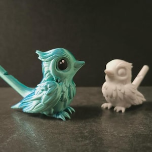 以下が含まれることがあります： 3Dプリントされた鳥の置物2つ。1つはティールブルー、もう1つは白。どちらも大きな目と細かい羽根が特徴です。