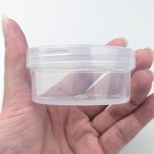 以下が含まれることがあります： ねじ込み式の蓋が付いた透明なプラスチック製の瓶。瓶は空で、滑らかで丸みを帯びた底をしています。