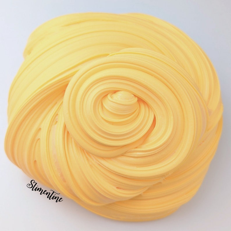May include: A close-up of a bright yellow slime, with a swirl pattern. The slime is soft and smooth, and it looks like it would be fun to play with.