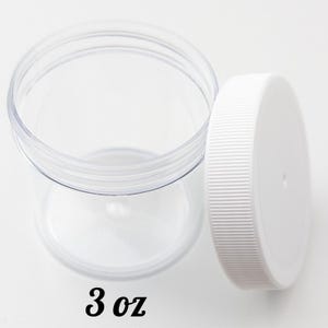May include: Clear plastic jar with a white lid. The jar is open, with the lid placed next to it. The text "3 oz" is printed in black at the bottom of the jar. The jar is designed for storage.