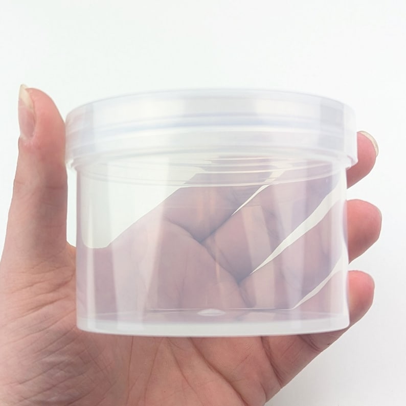 May include: Clear plastic container with a lid. The container is round and has a smooth surface.