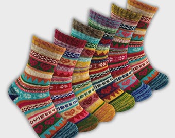 May include: Six pairs of patterned socks in a diagonal arrangement. Each sock displays a unique mix of stripes, geometric patterns, and heart designs in red, blue, yellow, and green. The socks are made of a thick, warm material.