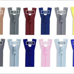 May include: A collection of twelve plastic zippers in various colors, each labeled with a numerical code: 007, 013, 021, 039, 134, 504, 195, 350, 228, 512, 542, and 918. The zippers are arranged in two rows, featuring shades of beige, gray, burgundy, blue, yellow, pink, and light blue.