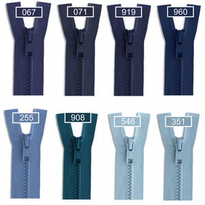 May include: Eleven plastic zippers arranged in two rows, displaying various shades of blue ranging from dark navy to light sky blue. Each zipper features a matching pull tab and a rectangular label with a white number: 560, 067, 071, 919, 960, 558, 920, 255, 908, 546, and 351.