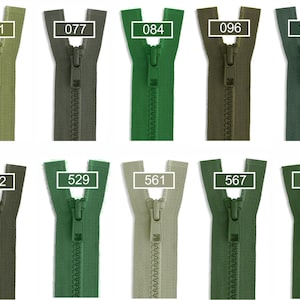 May include: A collection of ten plastic zippers in various shades of green, arranged in two rows. Each zipper features a matching pull tab and is labeled with a white rectangular box containing the specific color code numbers 011, 077, 084, 096, 153, 282, 529, 561, 567, and 880.