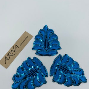 May include: Three blue sequined fabric appliques in the shape of a stylized leaf. The appliques have a black mesh backing and are perfect for adding a touch of sparkle to clothing or crafts.