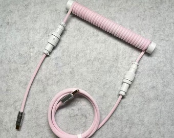 May include: A pink coiled cable with white connectors and a USB-C connector. The cable is coiled and has a white plastic clip to keep it organized.
