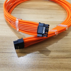 Puede incluir: Cable de ordenador naranja con conectores negros. El cable está trenzado y tiene varios cables.