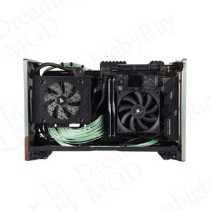 May include: A small form factor PC case with internal components visible. The case is light green with a dark brown base. Inside are black fans, a motherboard, and green cables. The components are neatly arranged.
