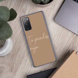 May include: A brown phone case with a white inscription that reads "Tú puedes, mija."