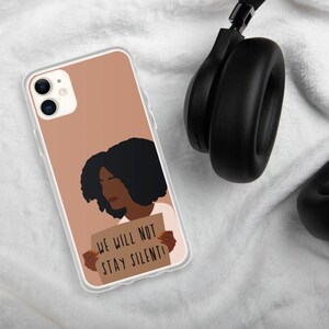 May include: A clear phone case with a brown background and a black and brown illustration of a person holding a sign that says "We will not stay silent!"