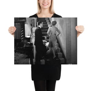 Könnte beinhalten: Ein Schwarzweißfoto von einem Mann und einer Frau, die auf einer Treppe stehen. Die Frau trägt ein Perlenkleid und der Mann einen Anzug. Das Foto ist im Vintage-Stil.