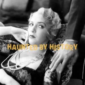 May include: A black and white photo of a woman wearing a black lace dress and a pearl necklace. The woman is sitting on a couch with a man's hand resting on her shoulder. The text "HAUNTED BY HISTORY" is superimposed on the image.