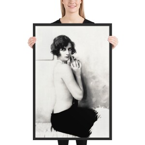 May include: A framed black and white photograph featuring a portrait of a person with short wavy hair, looking over their shoulder. The subject is partially draped in a dark garment, with a feathered texture visible along the lower edge of the frame.