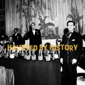 Puede incluir: Una fotografía en blanco y negro de un hombre hablando en un micrófono en un podio. El hombre lleva traje y corbata. Hay muchas estatuas pequeñas en la mesa frente a él. El texto "HAUNTED BY HISTORY" está superpuesto en la imagen.