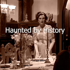 May include: A woman in a white dress and gloves stands in a dining room setting. The room is decorated in a vintage style with a wooden table, chairs, and a vase of flowers. The text "Haunted by History" is superimposed on the image.