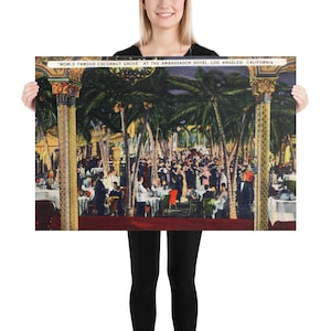 May include: A vintage postcard showing the "World Famous Coconut Grove" at the Ambassador Hotel in Los Angeles, California. The postcard depicts a lively scene of people dining and dancing under palm trees in a tropical setting.