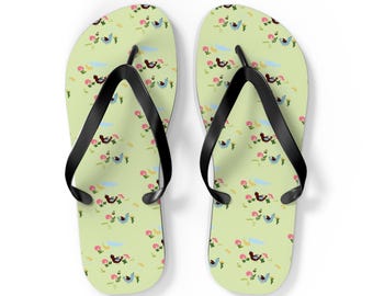May include: A pair of light green flip-flops featuring a repeating pattern of small brown birds, blue birds, and pink flowers. The footwear has black rubber thong straps attached to the soles, providing a simple and functional design for casual wear.