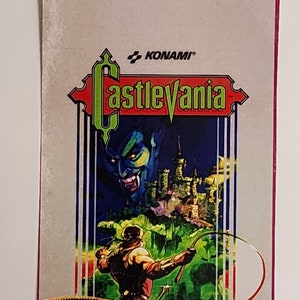 May include: A vintage video game cartridge for the Nintendo Entertainment System. The cartridge is for the game Castlevania, published by Konami. The front of the cartridge features a colorful illustration of a vampire and a man wielding a whip.